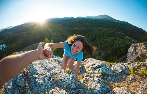 Woman climbing, smiling, and being helped up to show how our team of weight loss experts is ready to help