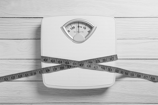 Scale with measuring tap around it to represent how many people feel about their weight