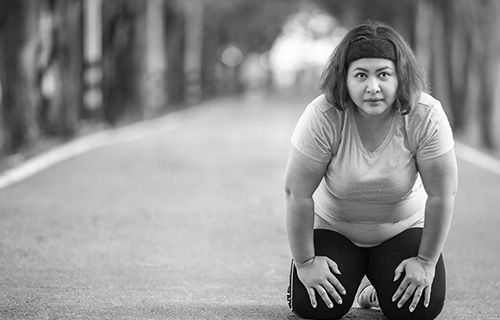 Woman kneeling after a run to show that we encourage physicl activity as part of our weigh loss plan