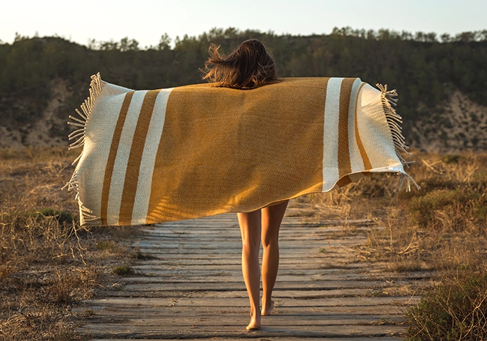 Woman walink away on wooden path outdoor with towel flowing to represent freedom that comes with healthy weight